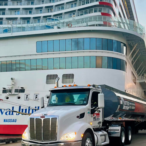 Midtex Oil tanker truck delivering marine fuel dockside beside a cruise ship on the Texas Coast.